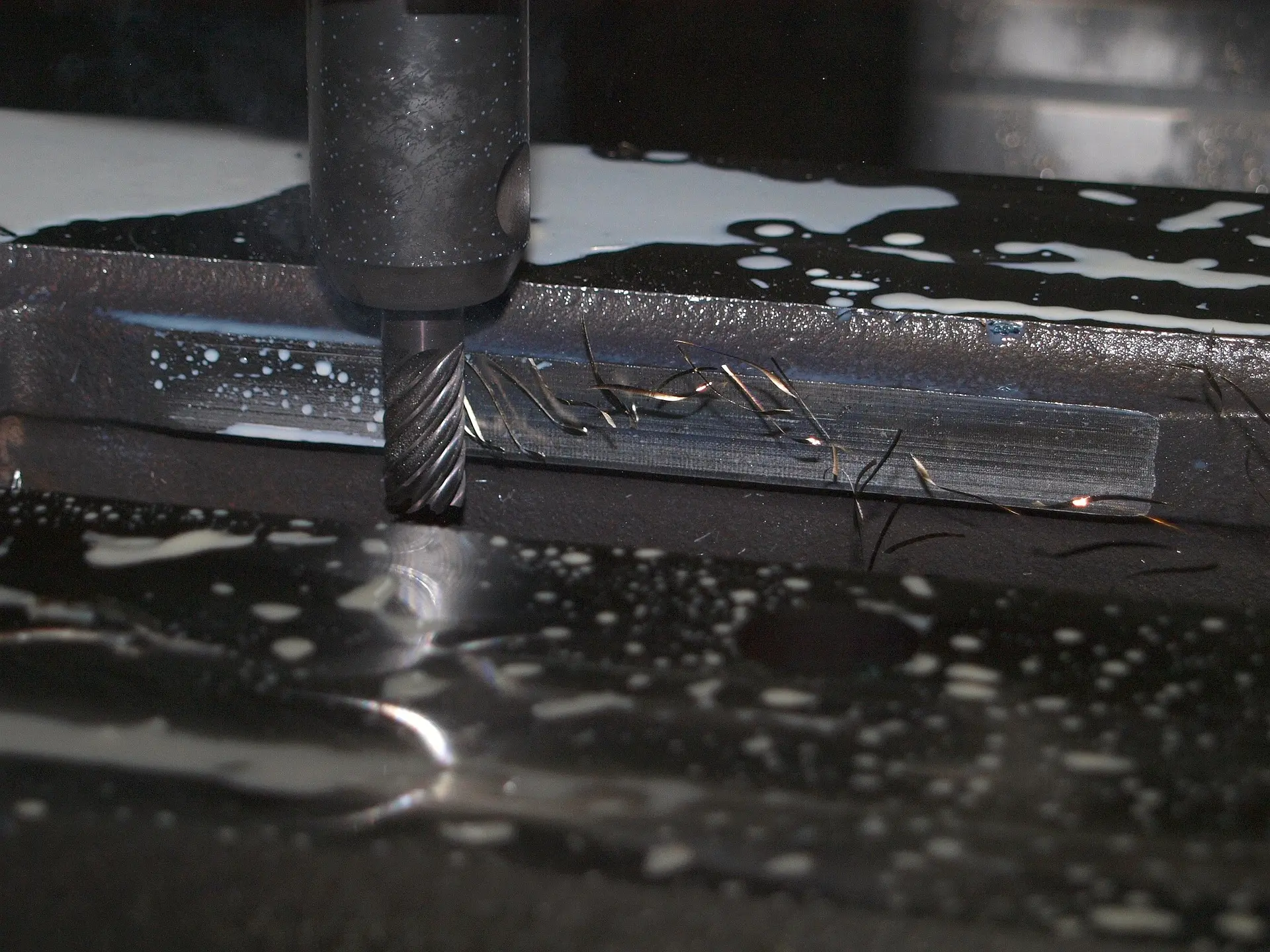 Fräswerkzeug, das auf einer Metalloberfläche mit Reinigungsflüssigkeit arbeitet.