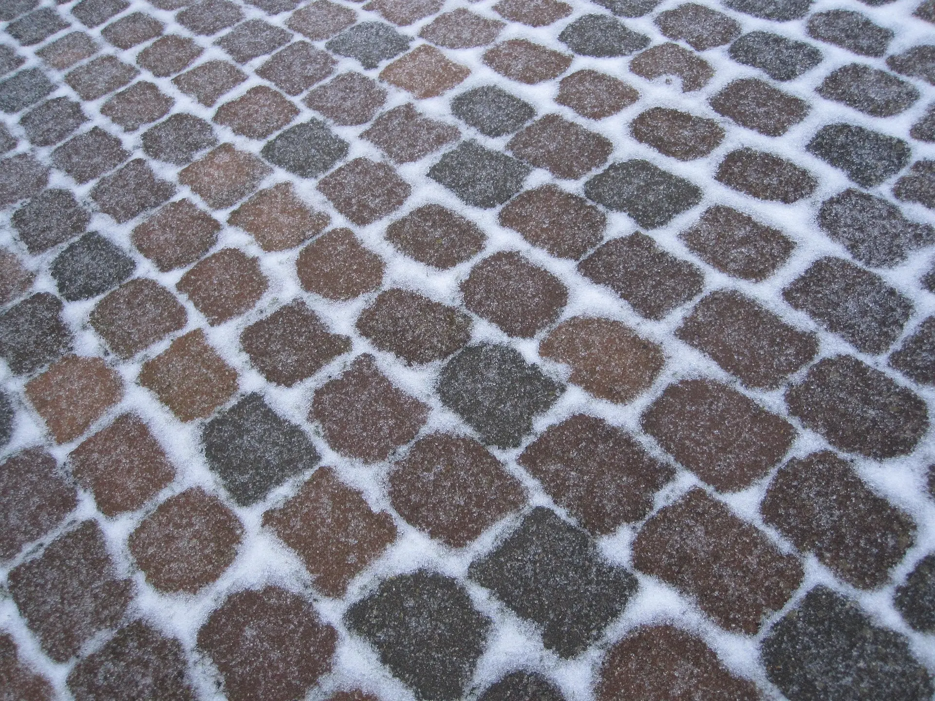 Pflastersteine in verschiedenen Farben, teilweise mit einer Schicht Schnee bedeckt.